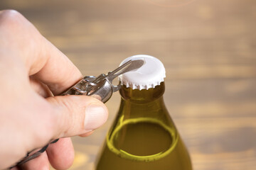 Metal corkscrew is opening of beer Bottle. Opener with cap close up.