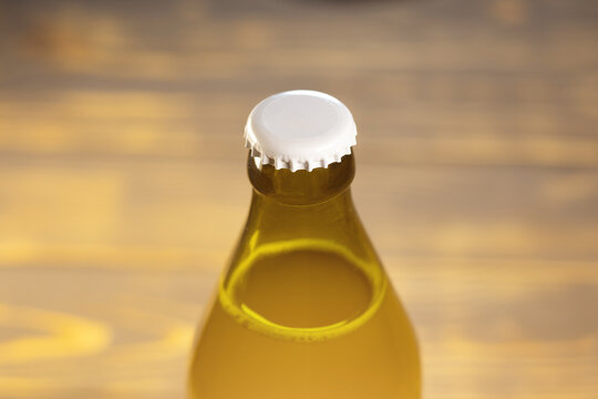Beer Bottle with white cap, close up on brown background.