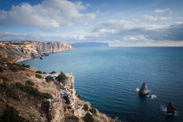 Fototapeta na wymiar High cliffs over the sea under a blue sky with clouds.