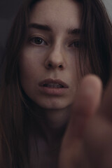 Portrait photo of a woman without makeup. Emotional photo of a woman. A hand reaches into the frame. Anxiety concept and asking for help
