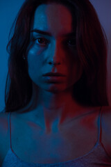 Portrait photo of a young woman in blue and red colors. The photo conveys anxiety, anger and stress.
