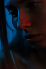 Intense young woman, blue and red lighting on face, 