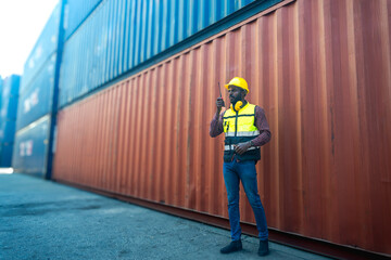Black container worker man holding hand radio working in container import export shipyard 