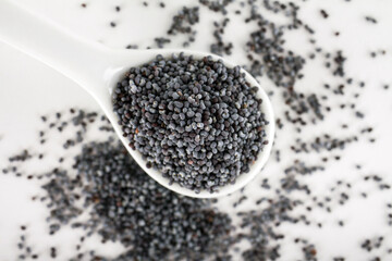 Spoon with poppy seeds on white background
