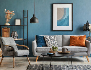 Creative composition of living room interior with mock up poster frame, grey sofa, black coffee table, blue wall, stylish furnitures, decorations and personal accessories. Template. Home decor