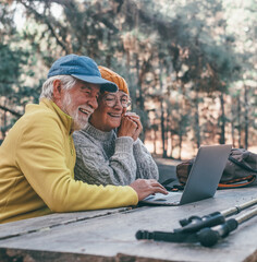 Head shot portrait close up of cute couple of old middle age people using computer pc outdoors...