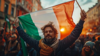 Flag of Ireland in hands of man, on background of crowd people during the celebration of St. Patrick's Day in irish city.