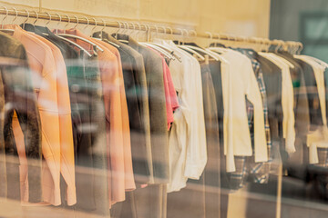 Women's clothing hangs on the rails. Blurred view through store window, selective focus