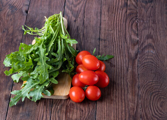 Fresh arugula and cherry tomatoes on a wooden table.