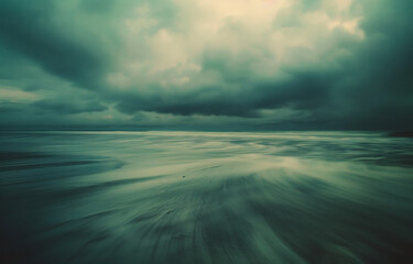 a photo of an empty beach with light and dark clouds  - obrazy, fototapety, plakaty