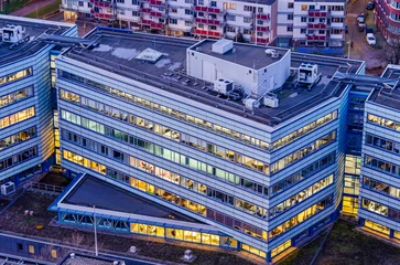 Fotobehang Rotterdam, The Netherlands, February 12, 2024: aerial view of an office building at dusk with the interior lighting on © Frans
