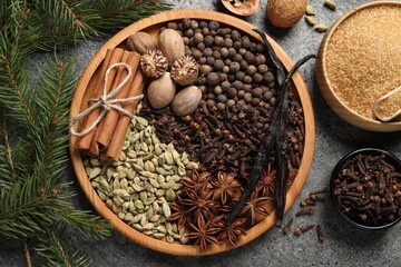 Different spices, nuts and fir branches on gray textured table, flat lay