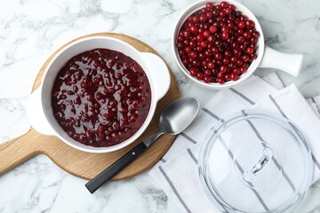 Fresh cranberry sauce in bowl served on white marble table, flat lay