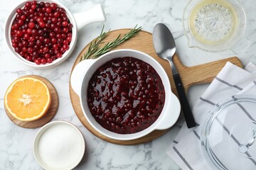Fresh cranberry sauce in bowl served on white marble table, flat lay