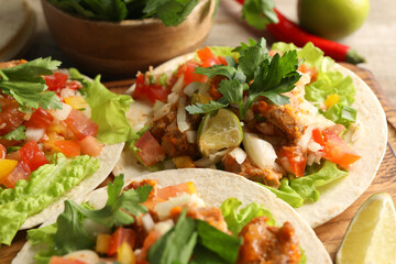 Delicious tacos with vegetables, meat and lime on table, closeup