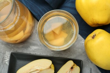Delicious quince drink and fresh fruits on grey table, flat lay