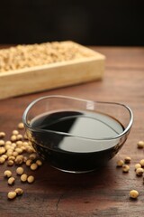 Soy sauce in bowl and soybeans on wooden table