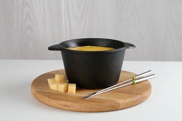 Fondue with tasty melted cheese and forks on white table