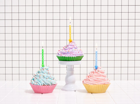 Cupcakes with colorful cream and sprinkles, festive candles. Concept of birthday party.
