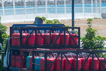 Red small cylinders for gas supply to the population, loaded on the back of a truck for delivery....