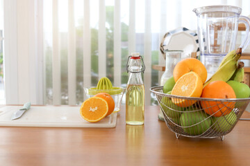 Fresh orange, green apple, banana in basket with milk, syrup bottle and smoothie blender on wooden...