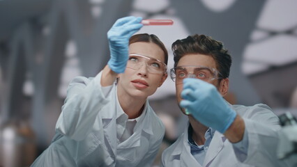 Two researchers examining vaccine sample in biotechnical laboratory close up.