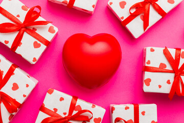 gift box with red bow and red heart on colored background . Top view. Flat lay