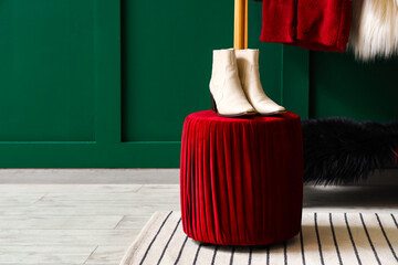 Pouf with stylish female boots near green wall in boutique