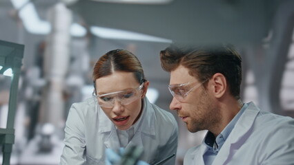 Two chemists examining test tube with medicines in advanced laboratory close up.