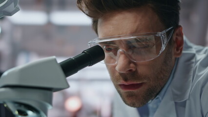 Pensive lab specialist working in genetics clinic closeup. Serious man scientist