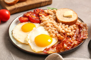 Plate of tasty English breakfast with fried eggs on grey background