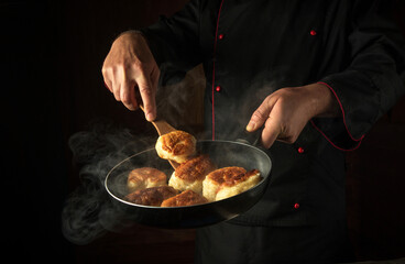 A cook fries donuts in a restaurant kitchen. A kitchen spatula in the hand of a cook and a frying...