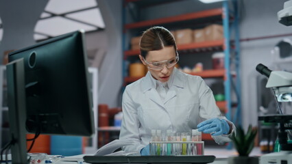 Lab expert checking test tubes making notes in clinic close up. Woman scientist