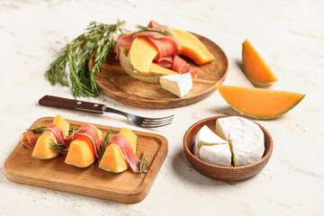 Composition with tasty melon, prosciutto and cheese on light background