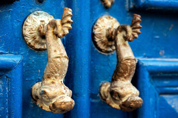 Closeup of ornate door knockers on an old blue door in Lisbon, Portugal