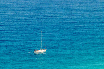 Velero navegando por aguas turquesas. Vista cenital de un velero navegando por el mar Mediterráneo. Playa de Los Muertos, Almería, España. - obrazy, fototapety, plakaty