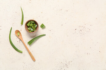 Bowl and spoon with cut aloe leaves on grunge background