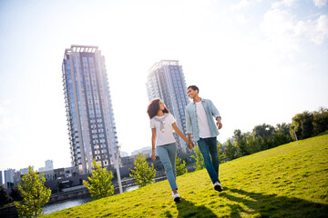 Photo of young couple holding hands and walking on the backyard together spend weekend vacation outdoors outside their house in town