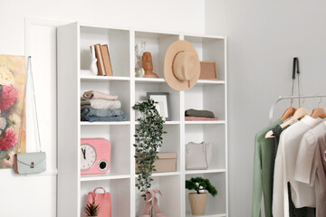 Interior of modern dressing room with stack of clean clothes on shelving unit