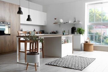 Interior of modern kitchen with white furniture and wooden island table