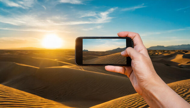 Hand holding a smart phone and taking pictures of the desert at sunset
