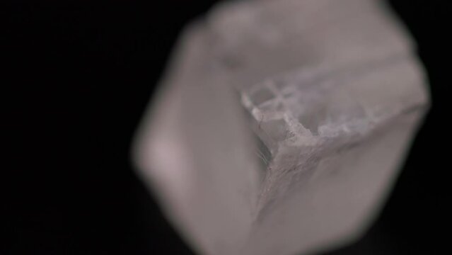 Iceland spar calcite mineral stone texture rotating on black background