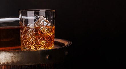 Whiskey glass with ice on a rustic barrel, a classic sip