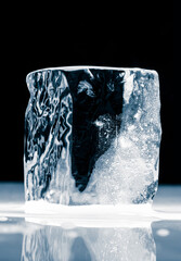 Crystal clear natural ice block on  black. background on a reflective surface.