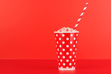 Paper cup with cola and ice over red background
