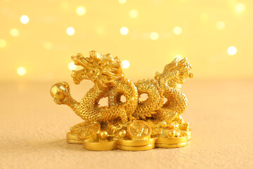Golden dragon figurine on yellow background, closeup. Chinese New Year celebration