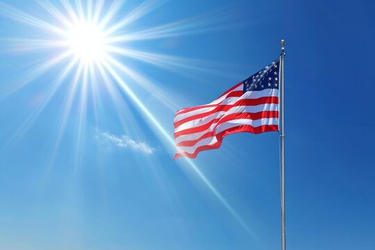The American flag flutters proudly in the wind on a sunny day against a blue sky. The concept of national patriotism and love for the motherland