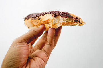 Close up hand holding bitten chocolate bread isolated on white background