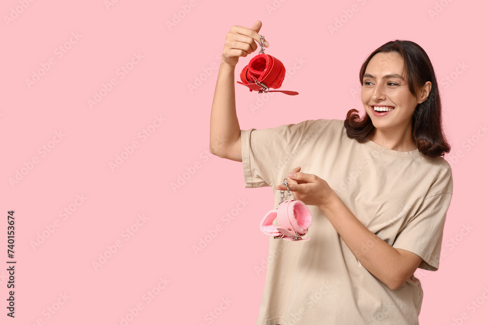 Wall mural beautiful young woman with handcuffs on pink background