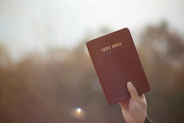 Person holding a Bible in the air